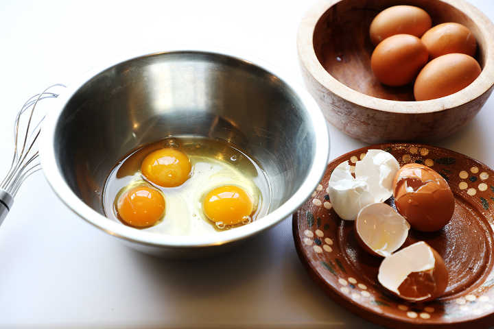 Huevos rotos en un tazón de acero inoxidable