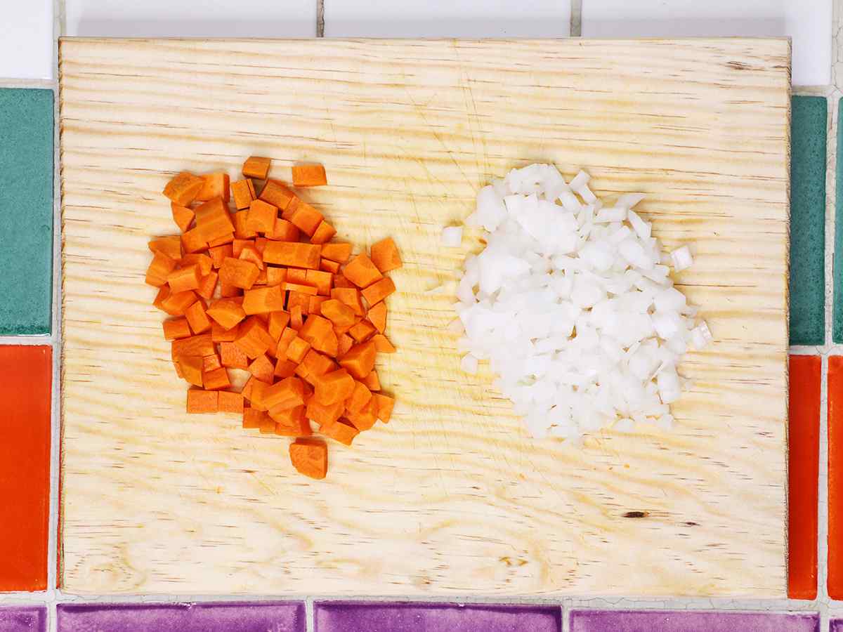 Zanahorias y cebollas cortadas en cuadritos en la tabla de cortar