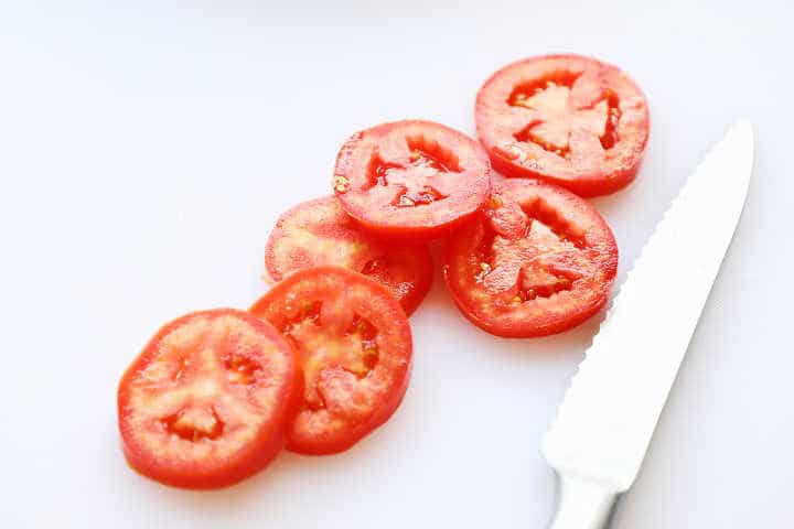 Rodajas de tomates ciruela en placa de corte